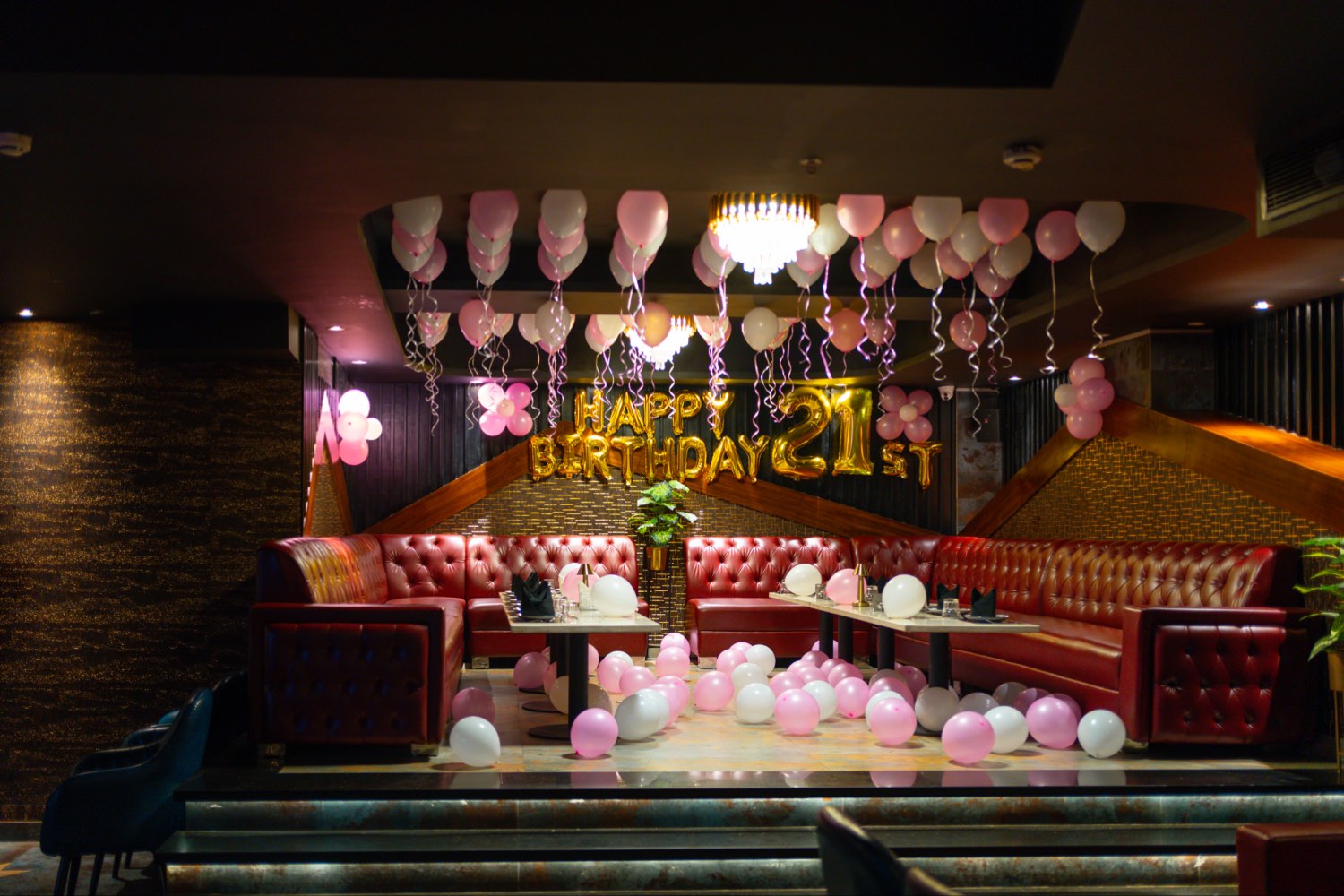 Bellers dressed for a twenty-first birthday, balloons over the red leather banquettes