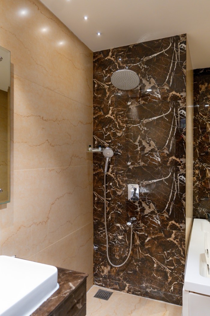 A bathroom in dark marble, the rain shower over the tiled floor